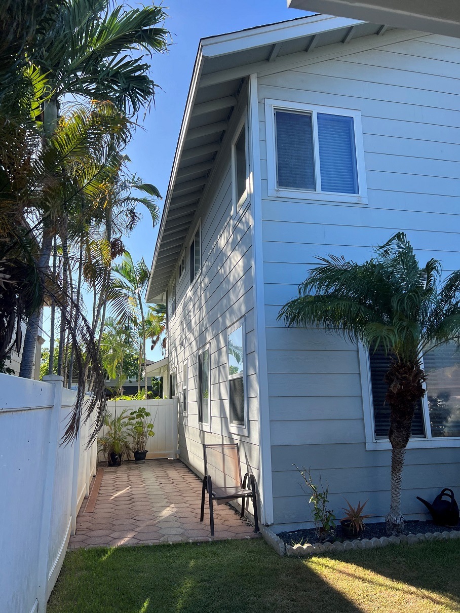 a side view of a white house with a patio and palm trees